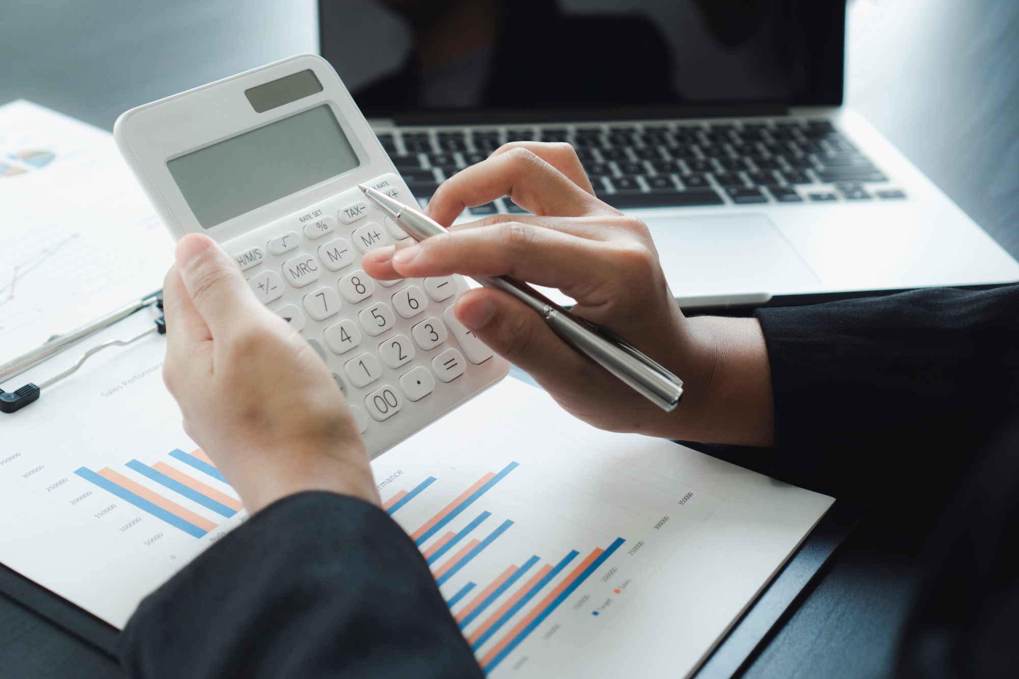 A businesswoman woman accountant or banker uses a calculator on the table at the office.